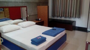 Una camera d'albergo con un letto grande, una scrivania, una sedia, una televisione e una finestra con tende.