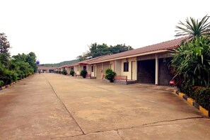 A row of single-story buildings with a flat roof, a paved walkway, and potted plants. - Zigzag Resort Mukdahan (Mukdahan)