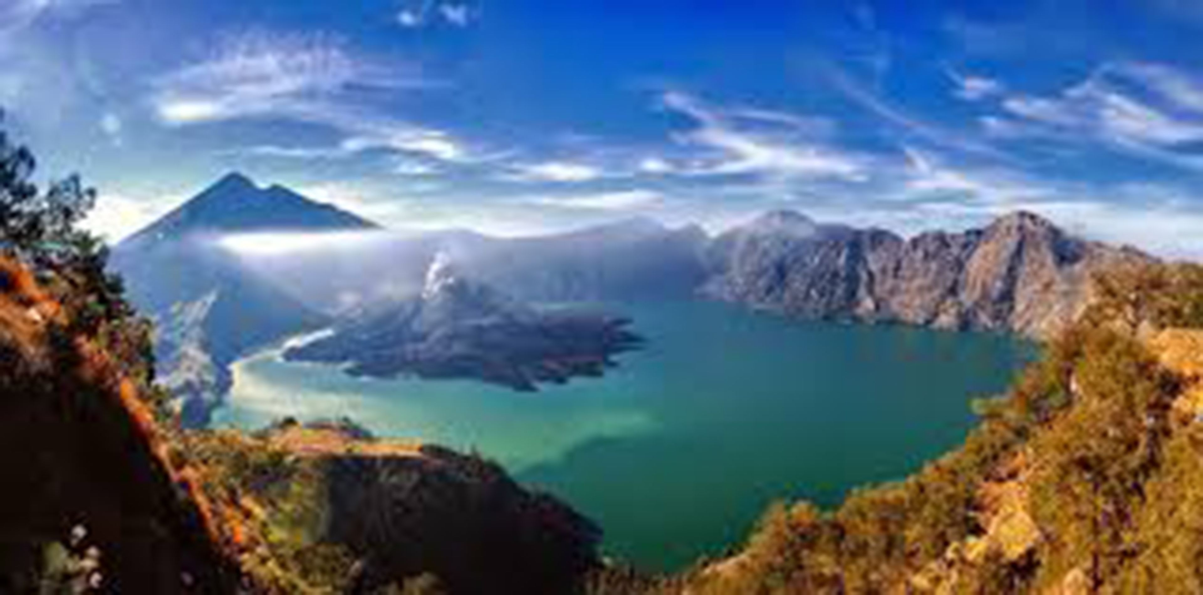 Una vista panorámica de un paisaje montañoso con un lago y un pico montañoso a lo lejos.