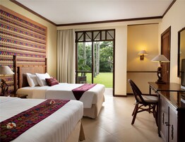 Habitación de hotel con dos camas, un escritorio, una silla, un ventanal grande y un adorno en la pared.