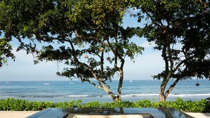 A modern infinity pool with a view of the ocean and boats. - Mangsit Suites by Holiday Resort Lombok (Senggigi)