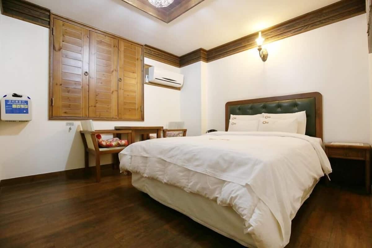 Ein ordentlich eingerichtetes Schlafzimmer mit einem großen Bett, einem Holzschrank, einem kleinen Tisch und einem Stuhl.
