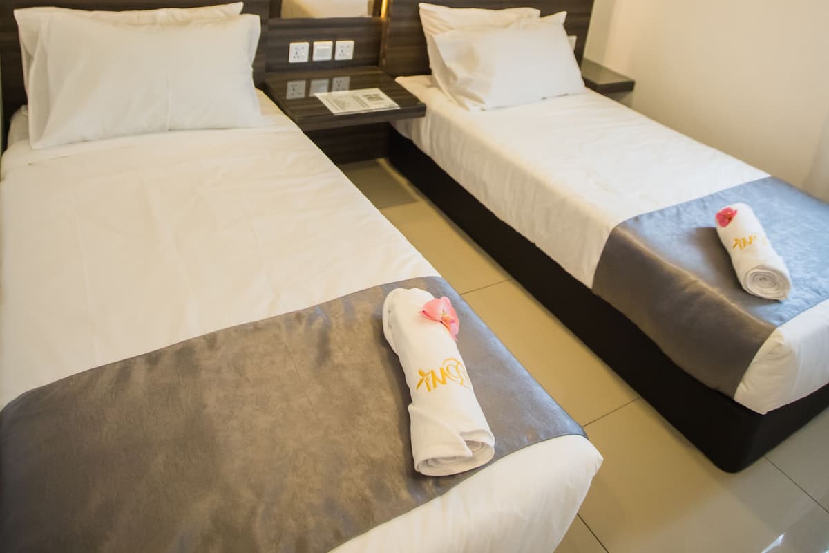 Une chambre d’hôtel avec deux lits simples, un grand miroir et un design moderne.