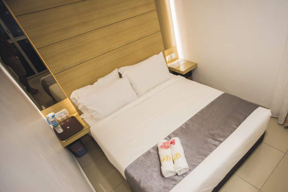 Une chambre d’hôtel avec un lit, une table de chevet, une serviette et un rideau.
