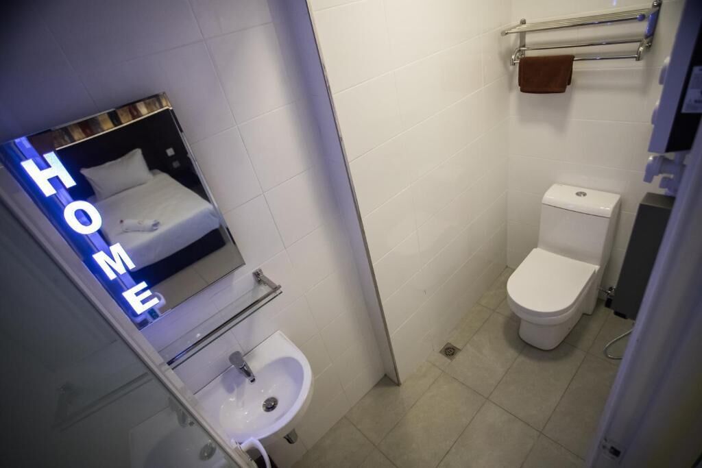 Un baño pequeño con inodoro, lavamanos y espejo.