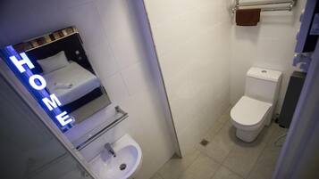 Un baño pequeño con inodoro, lavamanos y espejo.