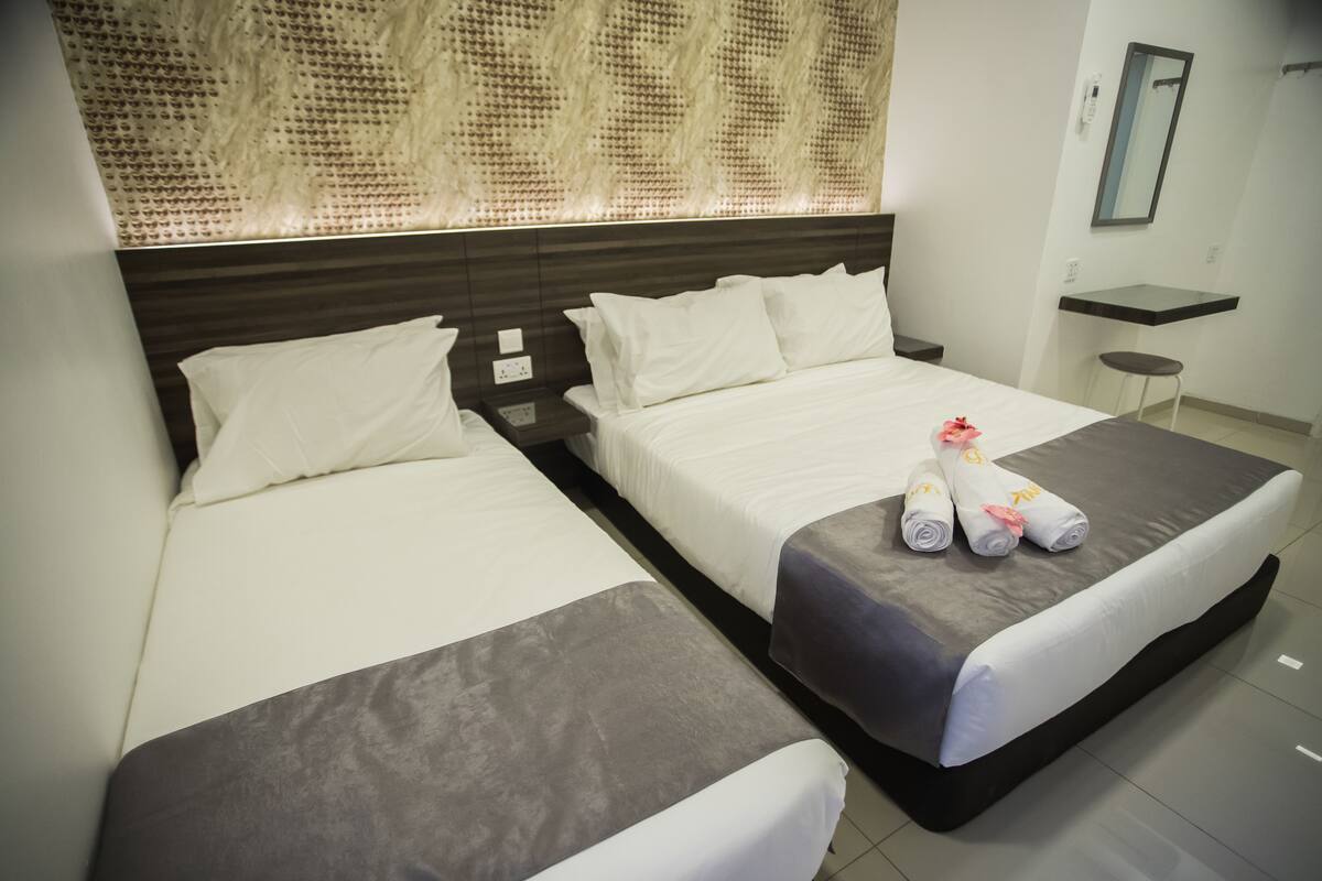 Une chambre d’hôtel avec deux lits, une petite table et un miroir.