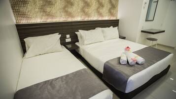 Habitación de hotel con dos camas, una mesita y un espejo.