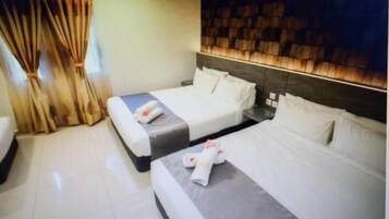 Een hotelkamer met twee bedden, een houten hoofdbord en een gordijn.