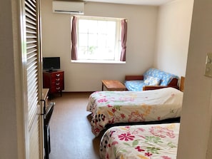 A bedroom with two beds, a TV, a small table, and a window with curtains. - Key West Club Okinawa (Onna)