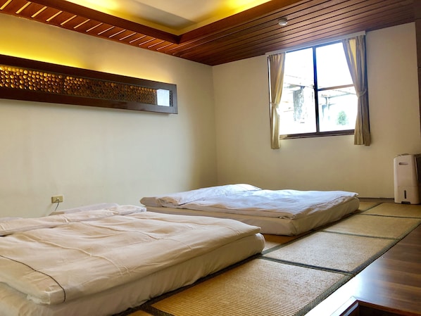 Una habitación con dos camas, una ventana con cortinas, aire acondicionado en la pared y un techo con vigas de madera.