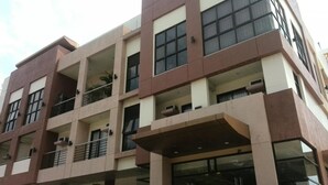 Un edificio de varios pisos con un diseño arquitectónico moderno, con balcones y ventanas amplias.
