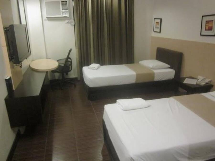 A hotel room with two beds, a small round table, a chair, a desk, and a telephone.