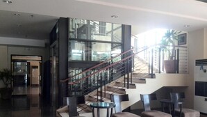 Un lobby moderno con una escalera de vidrio, un área de descanso y vistas del interior del edificio.