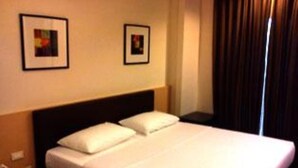 Habitación de hotel con una cama individual, dos almohadas y dos cuadros en la pared.