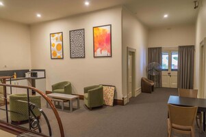 A hotel room with a dining area, a staircase, and artwork on the walls.