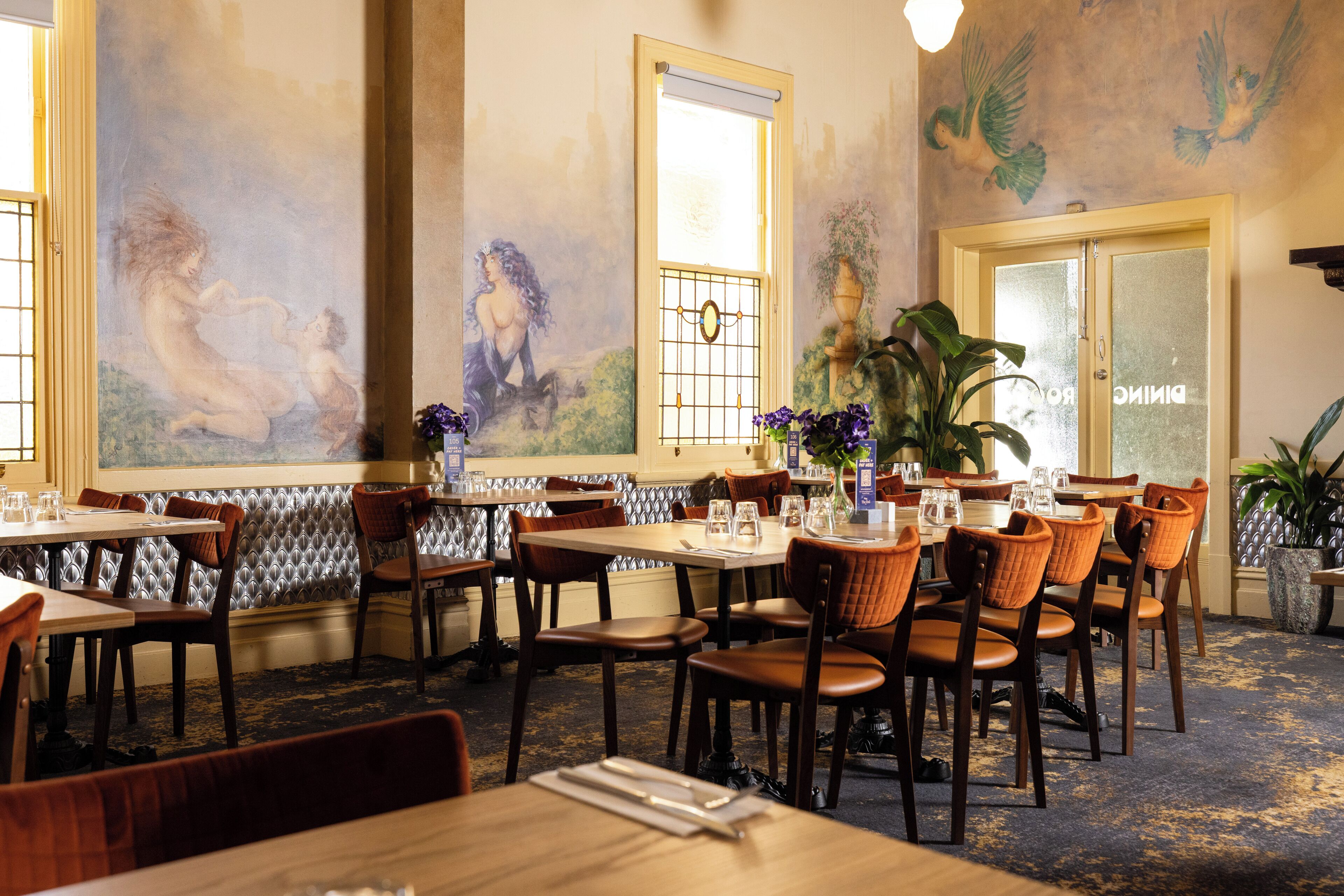 Un restaurant amb sostres alts, murals ornamentals i una decoració d'interior clàssica.