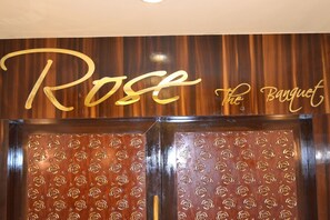 A wooden wall with the words "Rose The Banquet" in gold lettering.