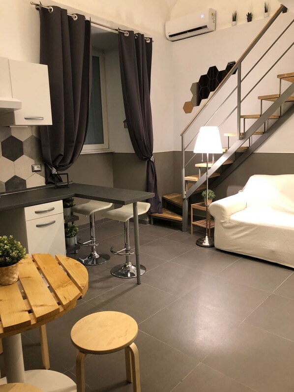 Een moderne keuken met een bar, een trap en een zithoek met een bank.