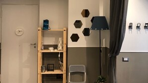 Ett modernt vardagsrum med en bokhylla i trä, en vit stol, ett litet bord med en växt och en lampa.