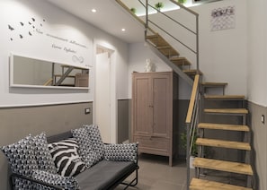 Een moderne woonkamer met een bank, een houten trap en een kledingkast.