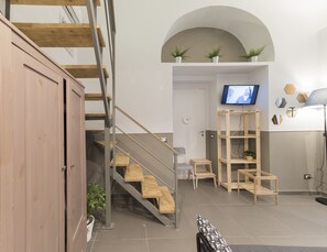 A modern interior with a staircase, wooden shelves, and a television. - La Casa di Ulisse (Naples)