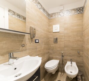 A modern bathroom with a sink, toilet, bidet, and a mirror. - La Casa di Ulisse (Naples)
