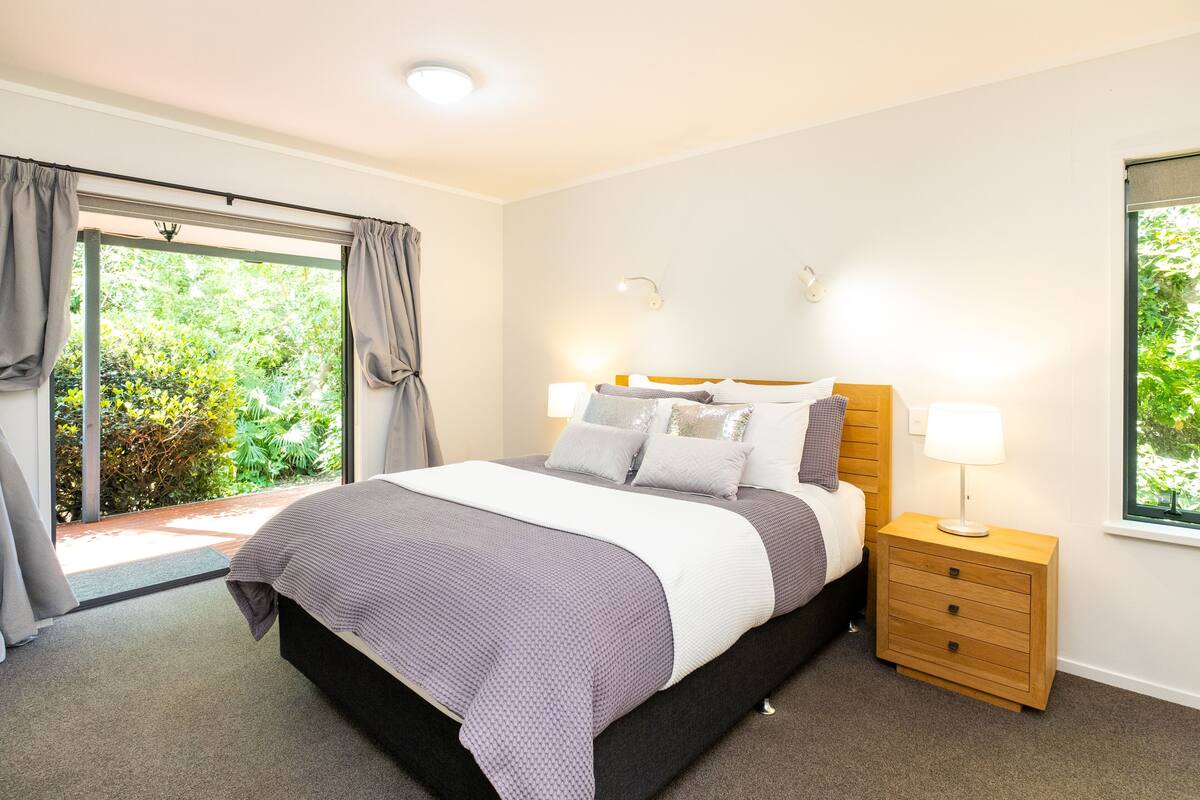 A bedroom with a bed, nightstands, and a window with curtains.
