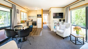 Een modern interieur met een eethoek, keuken en woonruimte, met grote ramen en een flatscreen televisie.