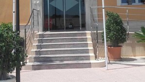 A hotel entrance with a flag, steps, and a sign.