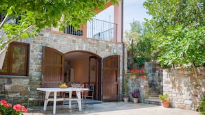 A stone building with a balcony, a wooden door, and a table with chairs outside. - Affittacamere Il Melograno (Pollica)