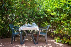 A table set with a white tablecloth and two chairs, surrounded by lush green foliage. - Affittacamere Il Melograno (Pollica)