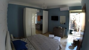 A bedroom with a bed, wardrobe, dresser, and a balcony with a table and chairs. - La Fenice Punto Zero (Naples)