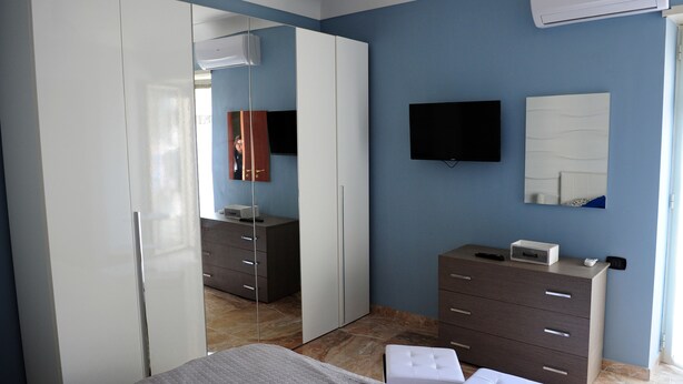 A bedroom with a bed, a dresser, a TV, and a wardrobe. - La Fenice Punto Zero (Naples)