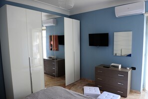 A bedroom with a bed, a dresser, a TV, and a wardrobe. - La Fenice Punto Zero (Naples)