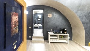 Un pasillo con una consola blanca, un reloj y una escalera que lleva a otra habitación.