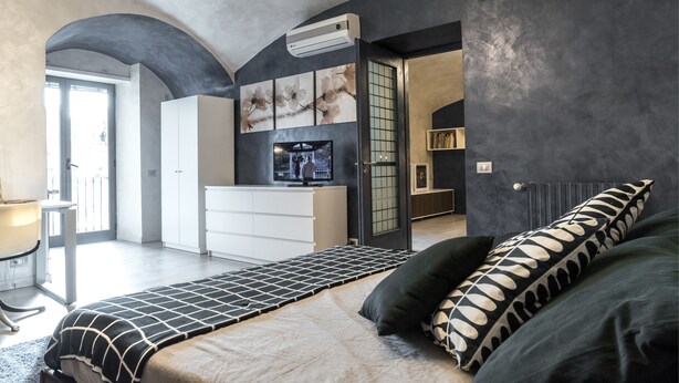 Un dormitorio moderno con cama, televisor y vistas al exterior.