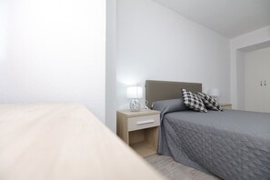 A minimalist bedroom with a bed, bedside table, and a nightstand.
