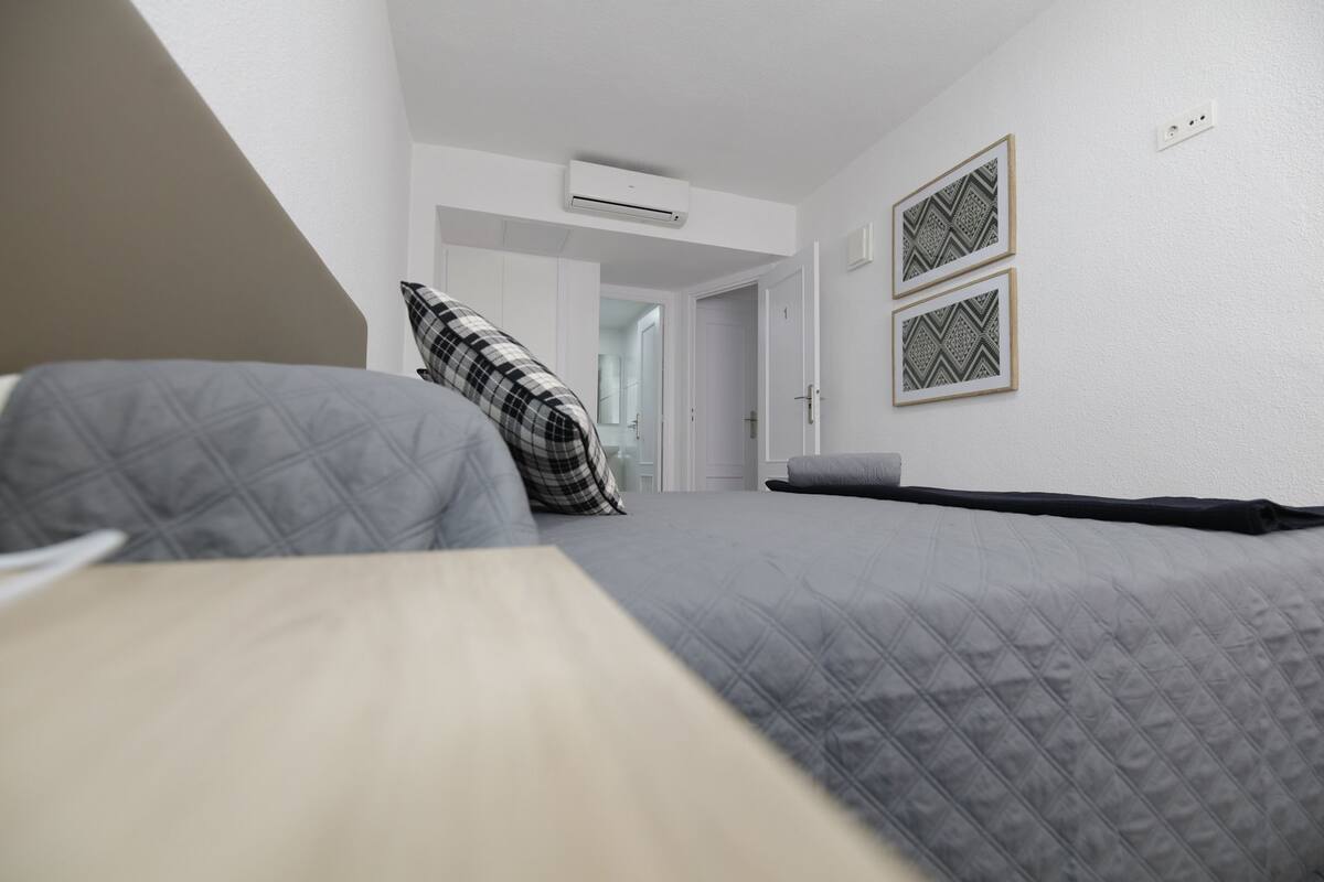 Een slaapkamer met een bed, een kussen, een nachtkastje en een kledingkast.