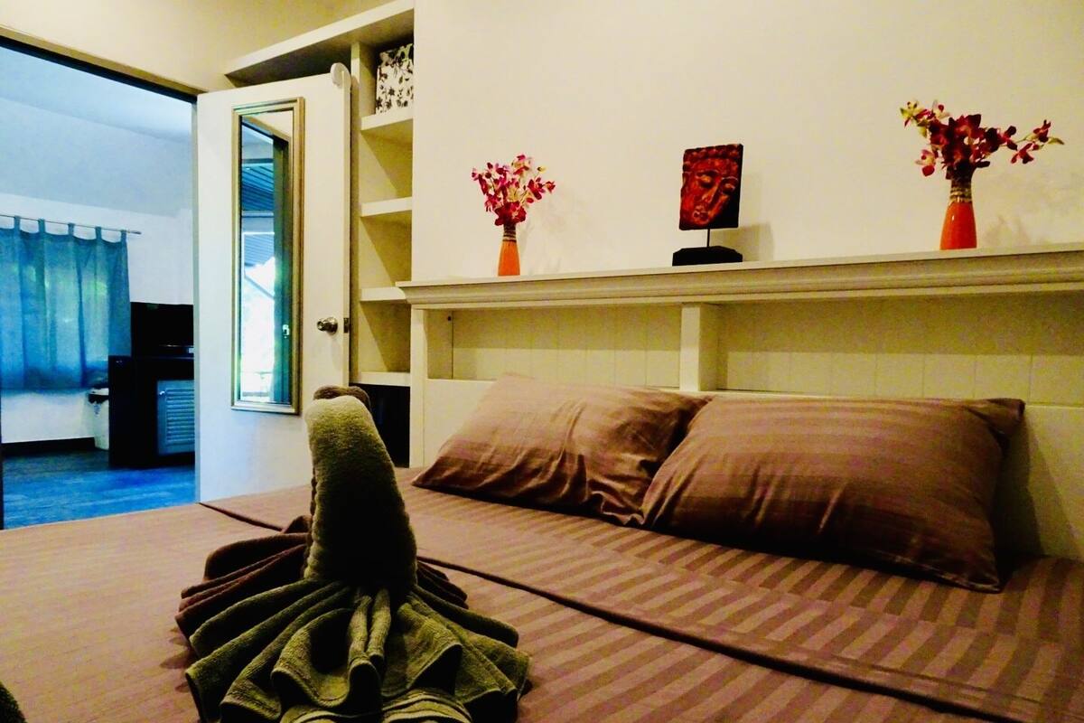 A hotel room with a bed, a robe, and a view of the hallway.