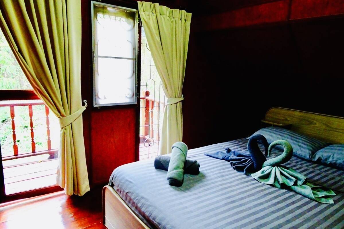 A room with a bed, curtains, a window, and a view of the outdoors.