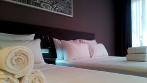 A hotel room with two beds, white linens, rolled towels, a dark headboard, and a framed picture on the wall. - The Loft Plaza Hotel (Kajang)
