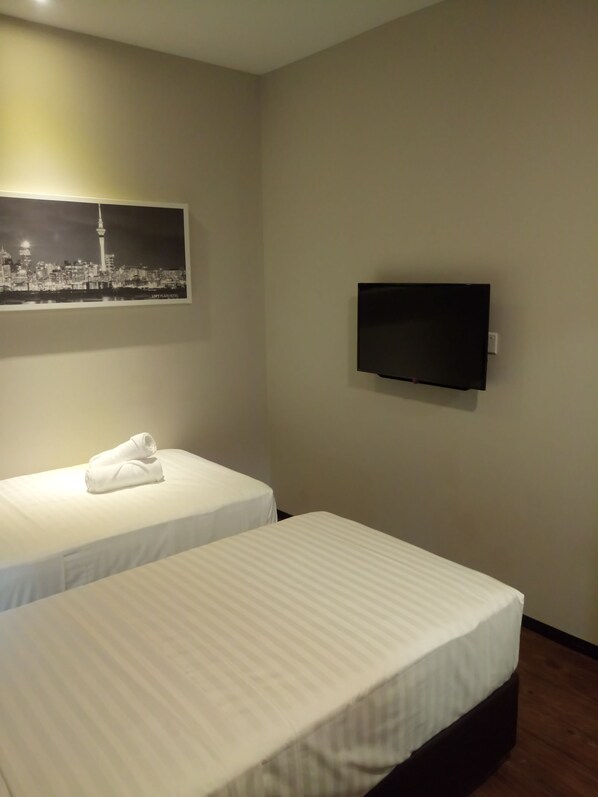 A hotel room with two beds, a flat-screen TV mounted on the wall, and a cityscape picture above the beds. - The Loft Plaza Hotel (Kajang)