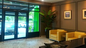 A reception area with a chandelier, two yellow chairs, a large potted plant, and framed pictures on the wall. - The Loft Plaza Hotel (Kajang)