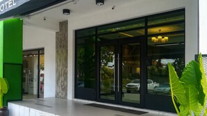 A hotel entrance with a black awning, large glass doors, and a visible car parking area. - The Loft Plaza Hotel (Kajang)