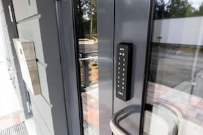 A modern elevator with a digital keypad, glass doors, and a metal handle. - Hiisi Homes Riihimäki (Riihimaki)