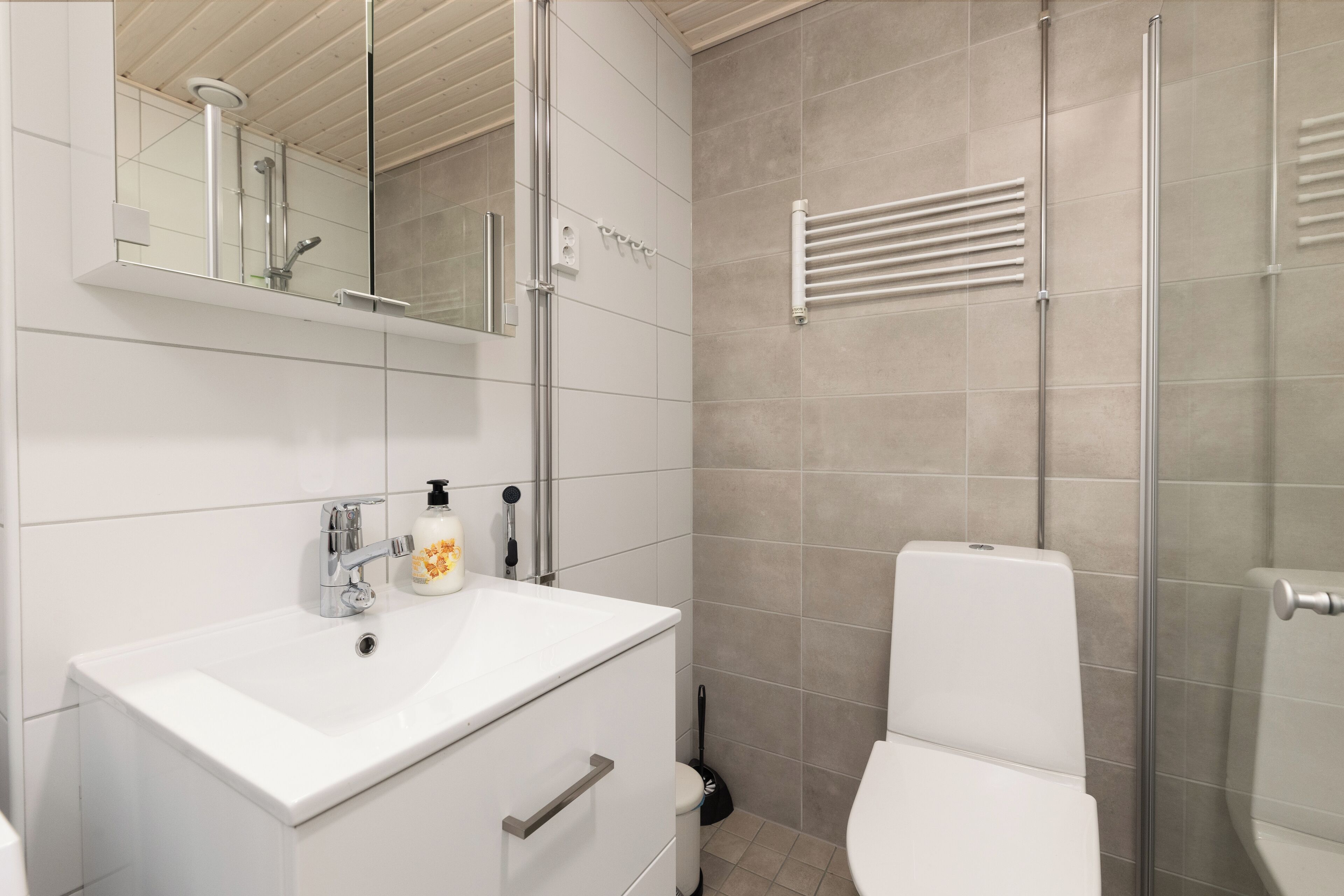 A modern bathroom with a white sink, mirror, and toilet.