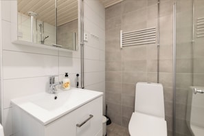 A modern bathroom with a white sink, mirror, and toilet. - Hiisi Homes Riihimäki (Riihimaki)