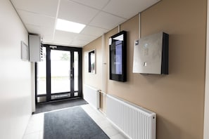 A hallway with a radiator, a door, and a mounted screen. - Hiisi Homes Riihimäki (Riihimaki)