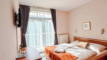 A hotel room with a bed, bedside table, and a window with curtains.